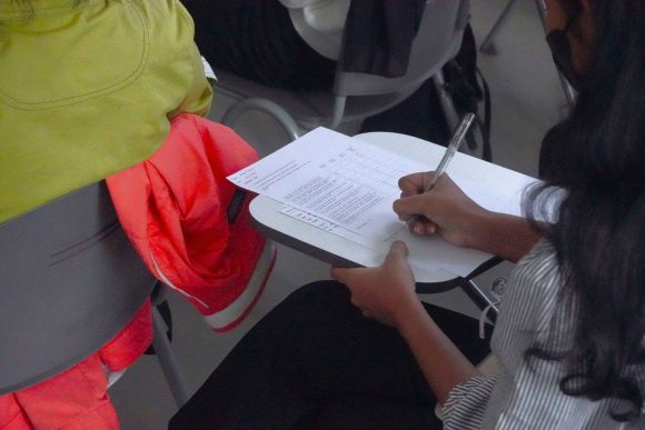 woman sat at a desk completing a survey with her right hand